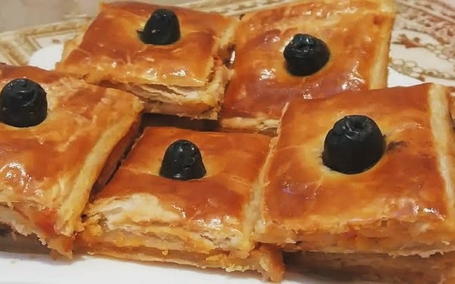 Coca algérienne, tourte dorée découpée en parts.