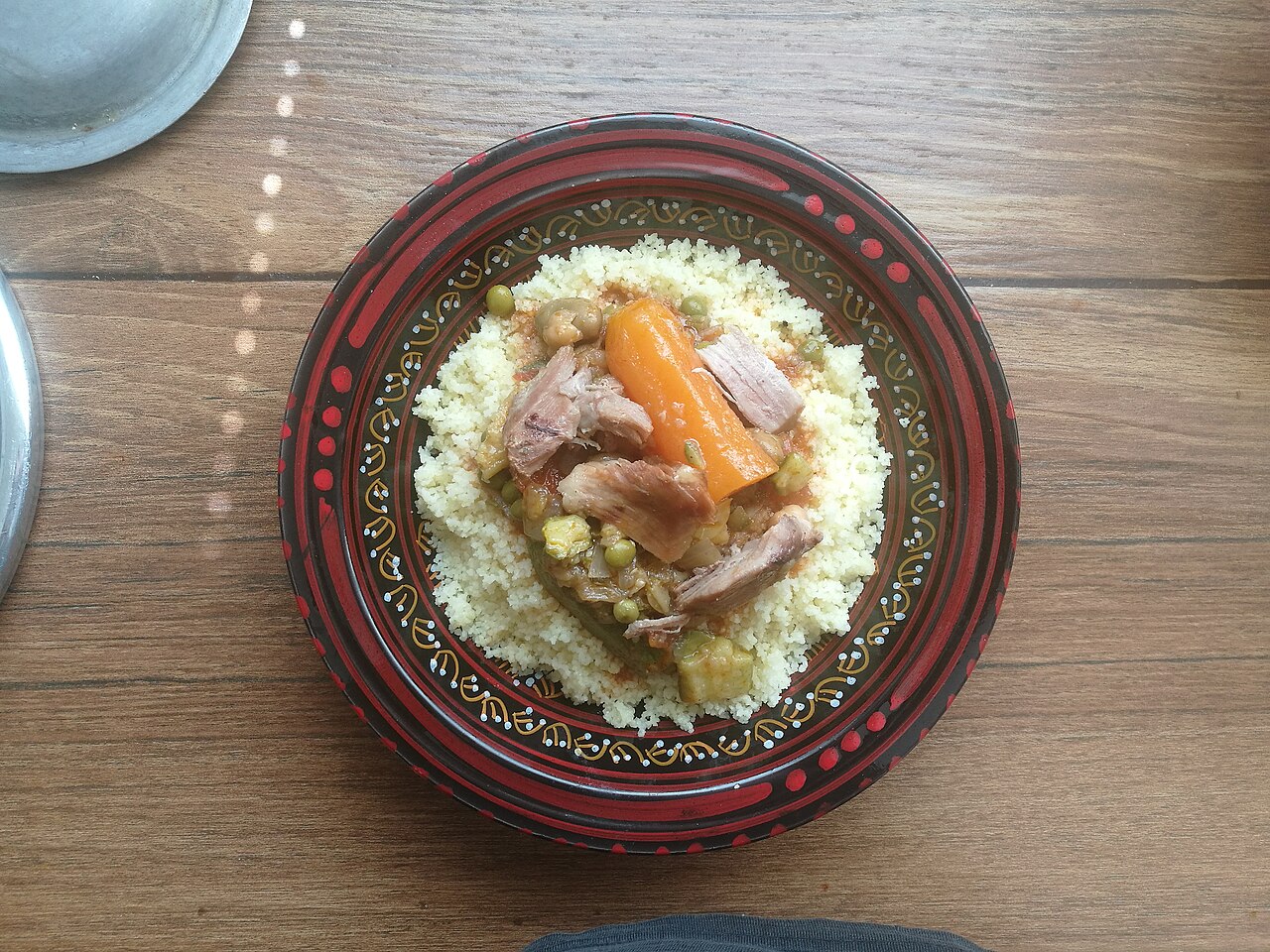 Assiette de couscous photographiée à Oran, garnie de légumes et de morceaux de viande.