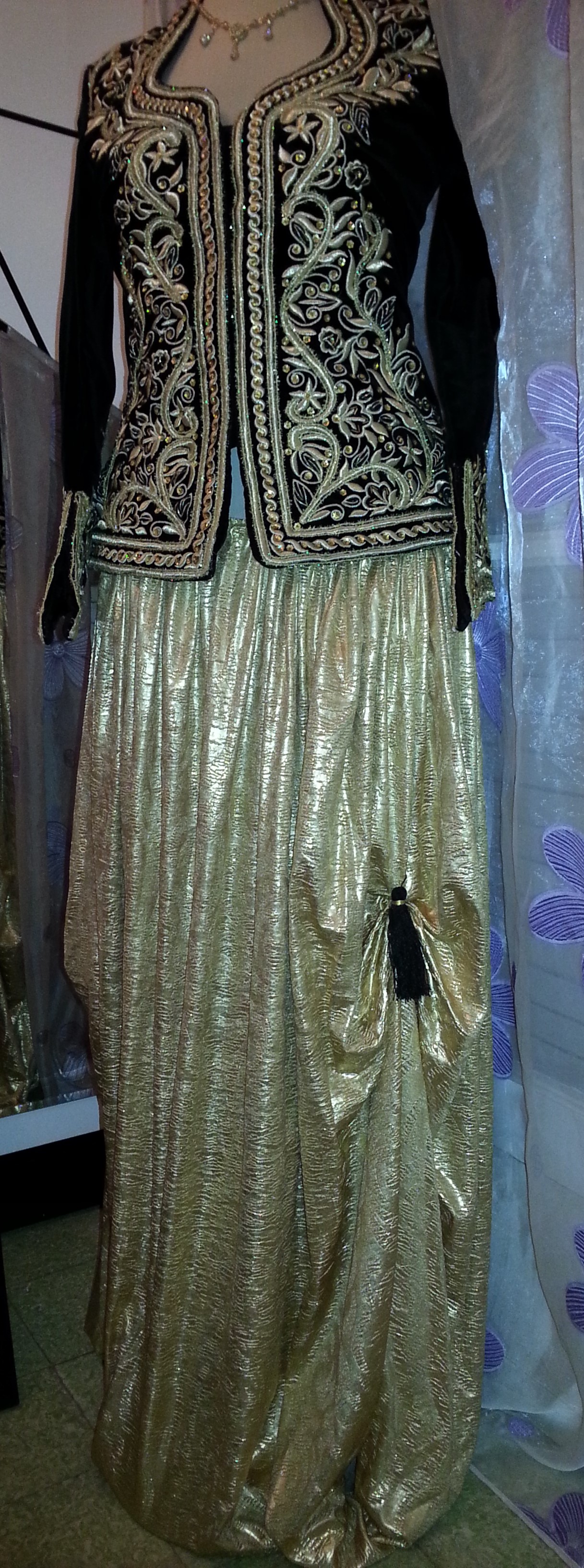 Karakou algérois noir brodé de motifs dorés, présenté avec un pantalon doré.